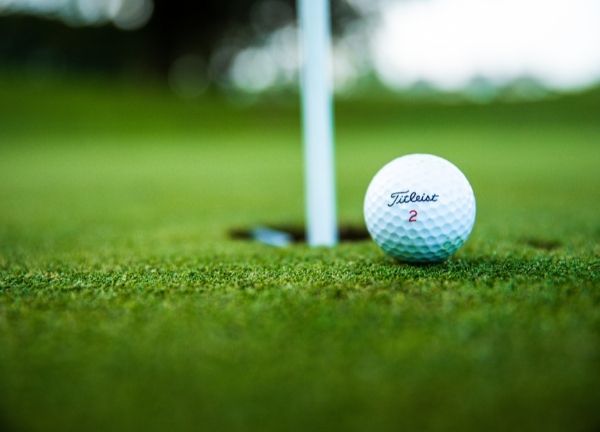 A golf ball on the edge of a hole.