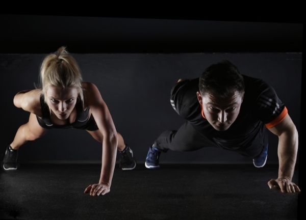 A man and woman doing one-armed pushups.